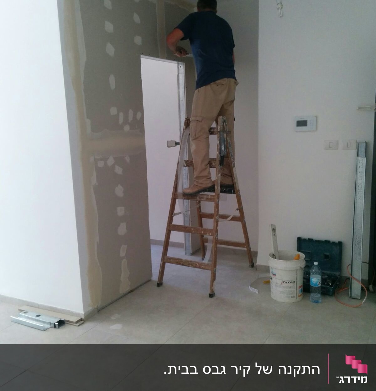 אדם על סולם עובד על קיר גבס